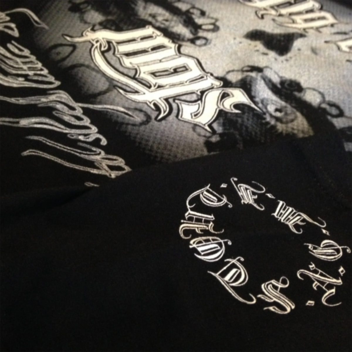Close-up of a black Sleep Bitch shirt with translucent imagery on a dark background